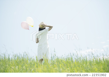 A rear view of a woman with a balloon in the meadow A rear view of a woman with a balloon in the meadow 22351902
