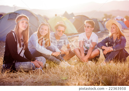Teenagers sitting on the ground in front of tents 22363938