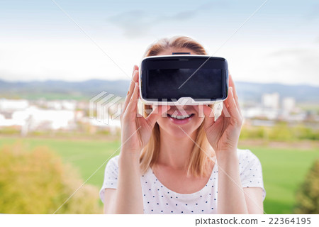 Woman wearing virtual reality goggles standing in 22364195