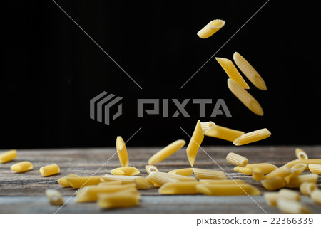 Falling penne pasta. Flying yellow raw macaroni 22366339