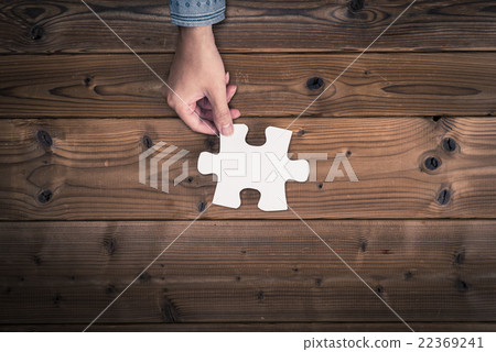 Human hand holding a piece of a jigsaw puzzle 22369241