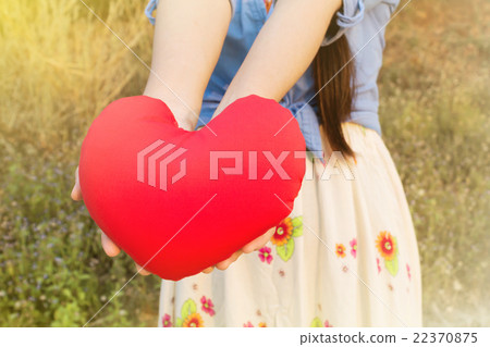 Women hand gently hold red heart on wild grass flower field back 22370875