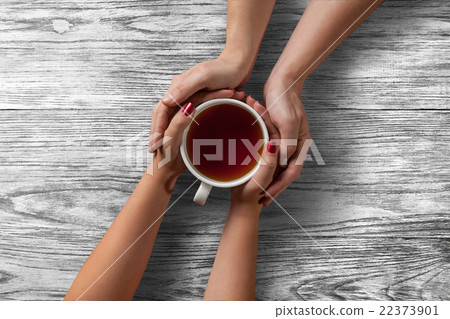 woman holding hot cup of tea with cookies 22373901