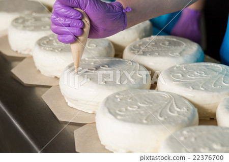 Hand with tool decorating cake. 22376700