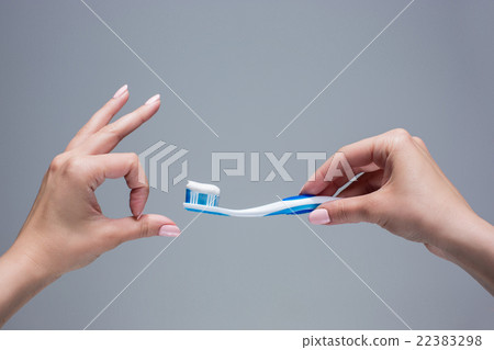 Toothbrush in woman's hands on gray Toothbrush in woman's hands on gray 22383298