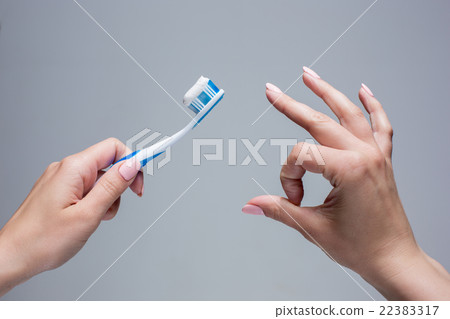 Toothbrush in woman's hands on gray Toothbrush in woman's hands on gray 22383317