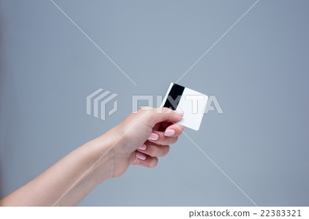 The card in a female hand is on a gray background 22383321