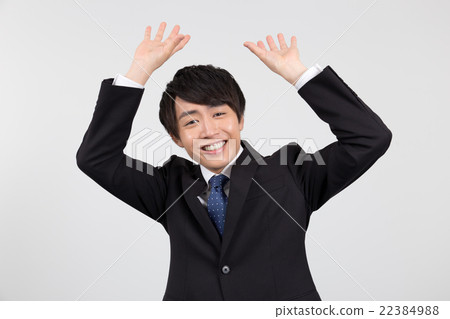 A young businessman (raising his hand) _ Looking at the camera 22384988