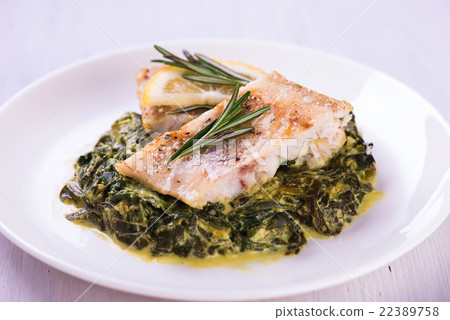 white fish fillet with herbs on fried spinach 22389758