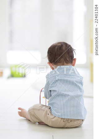 Behind the boy sitting on the floor 22401384