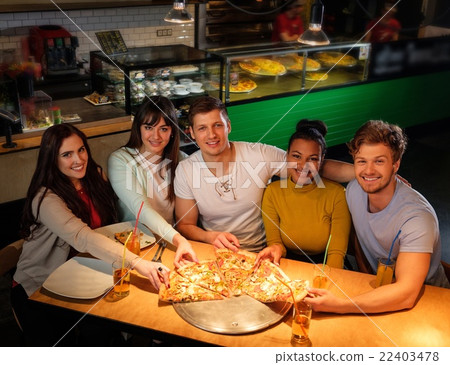 Multiracial friends eating pizza in pizzeria. 22403478
