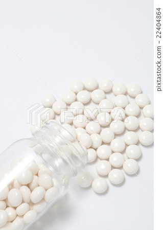 White pills spilling from a fallen transparent bottle 22404864