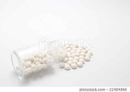 White pills spilling from a fallen transparent bottle 22404866