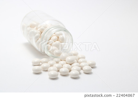 White pills spilling from a fallen transparent bottle White pills spilling from a fallen transparent bottle 22404867