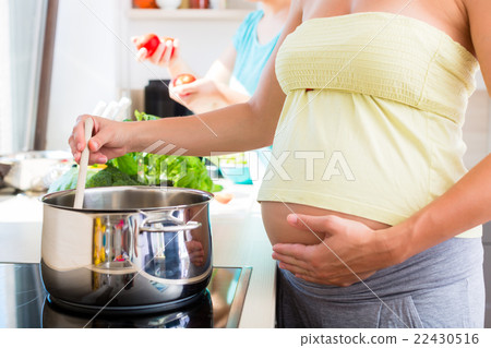 Pregnant woman cooking with best friend Pregnant woman cooking with best friend 22430516