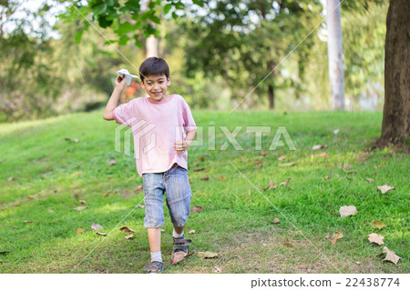 Little sibling boy playing plane paper in the park 22438774