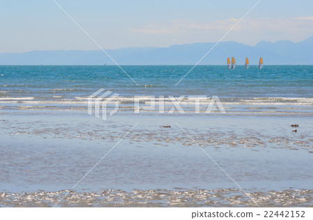 Wind surfing in a pale blue sea 22442152