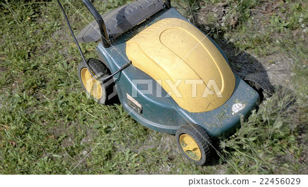 Mowing grass in the garden with electrical machine 22456029
