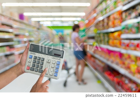 Hand touching buttons of calculator on the Abstract blurred photo of store in department store bokeh background 22459611