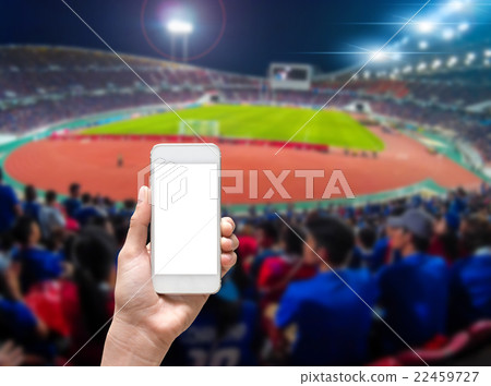 Hands holding smart mobile taking photo on the Abstract blurred photo of soccer stadium, sport background concept 22459727