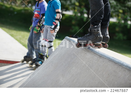 Aggressive inline rollerblader standing on ramp Aggressive inline rollerblader standing on ramp 22467887