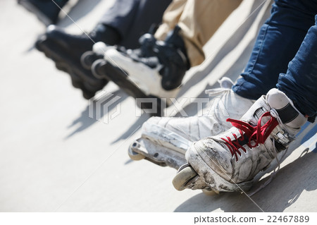 Aggressive inline rollerblader sitting on ramp Aggressive inline rollerblader sitting on ramp 22467889