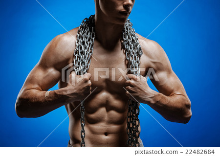Muscular guy with chains on his shoulders against Muscular guy with chains on his shoulders against 22482684