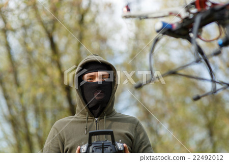 Man in mask operating a drone with remote control. 22492012