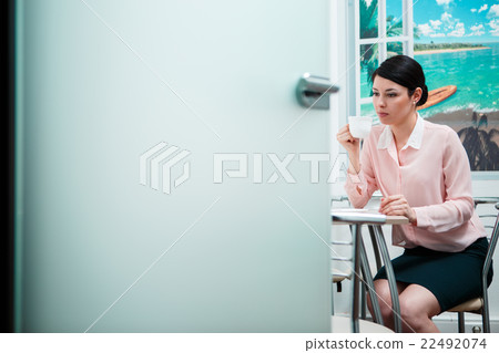 Woman drinking coffee in office kitchen 22492074