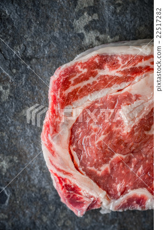 Piece of Ribeye steak on a marble gray-blue slate Piece of Ribeye steak on a marble gray-blue slate 22517282