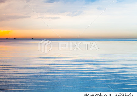 Still blue sea water under colorful sky 22521143