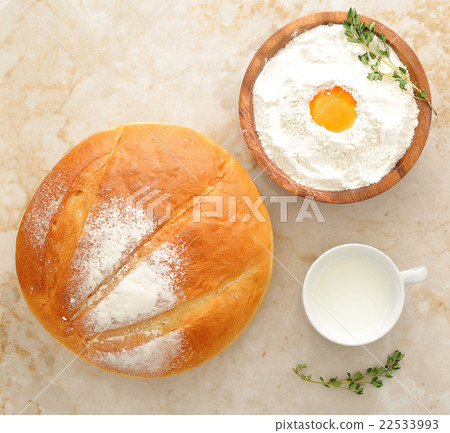 Round loaf of bread, milk in a Cup and the flour 22533993