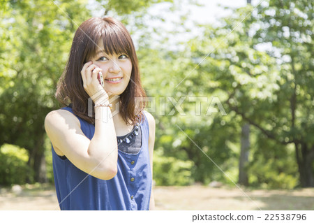 A woman using a smartphone in a park A woman using a smartphone in a park 22538796