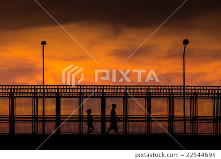 Silhouette of people walking on overpass Silhouette of people walking on overpass 22544695