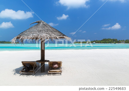 palapa and sunbeds by sea on maldives beach 22549683