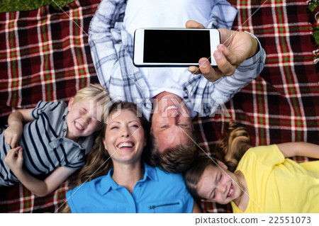 Happy family taking a selfie while lying in the park Happy family taking a selfie while lying in the park 22551073