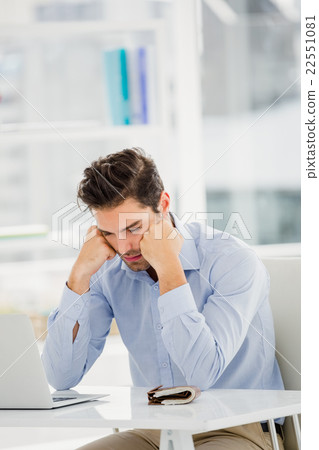 Tensed businessman sitting at table with laptop Tensed businessman sitting at table with laptop 22551081