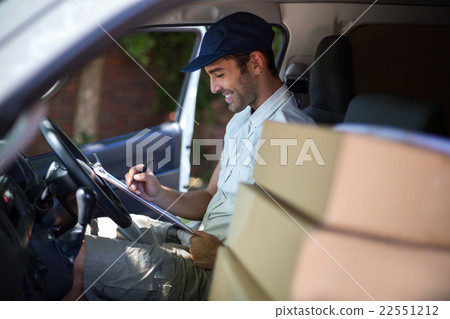 Smiling delivery man writing in clipboard Smiling delivery man writing in clipboard 22551212