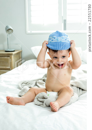 Cute baby boy wearing knit hat on bed 22551780