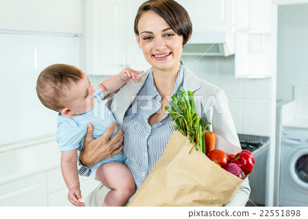 Businesswoman carrying son while holding vegetables 22551898