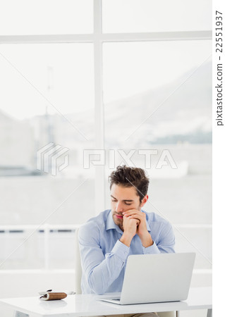 Tensed businessman sitting at table with laptop Tensed businessman sitting at table with laptop 22551937