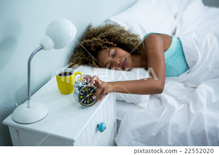 Woman stopping alarm while sleeping on bed Woman stopping alarm while sleeping on bed 22552020