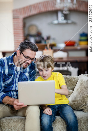 Father and son using laptop in living room Father and son using laptop in living room 22552642