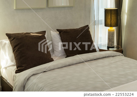 brown pillows on bed with lamp 22553224