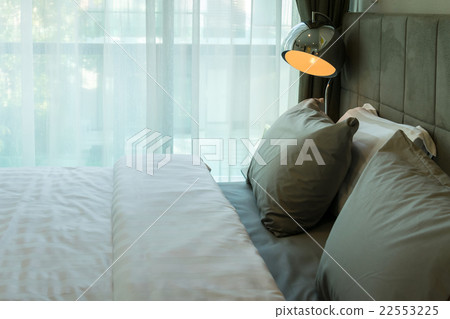 metal desk lamp and grey pillow on bed 22553225