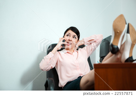 Relaxed business woman sitting in a chair with 22557871