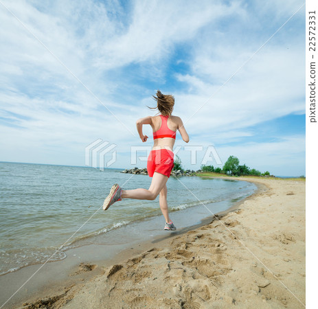 Young lady running at the sunny summer sand beach 22572331