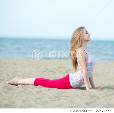 Young lady practicing yoga. Workout near ocean sea 22572332