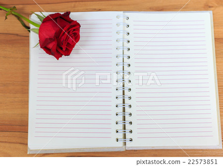 rose and empty notebook page on wood table 22573851