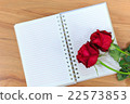 Red rosed with notebook on wood table. 22573853